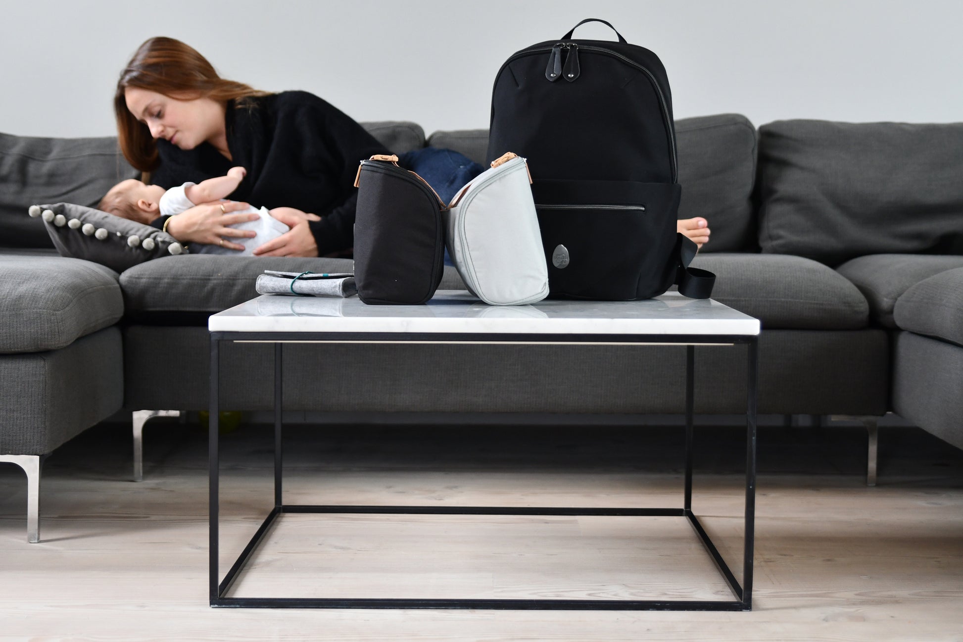 lady with baby lying down cuddling in front of the baby changing bag