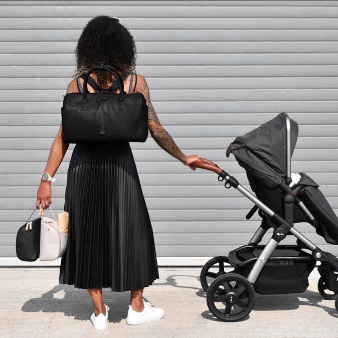 Woman wearing with the Firenze Pack as a backpack while pushing a pram