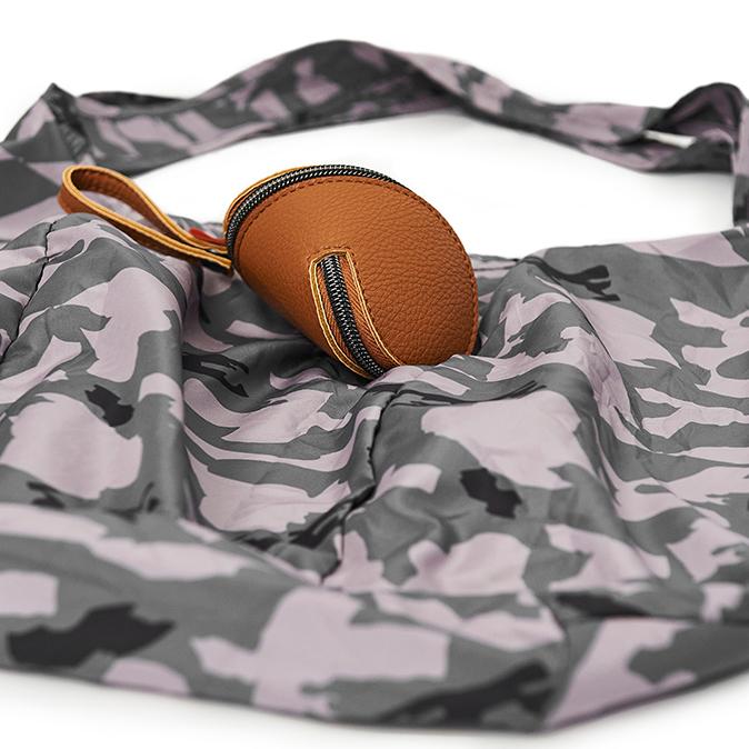 Camo pacsac flat on a surface with the tan case lying on top