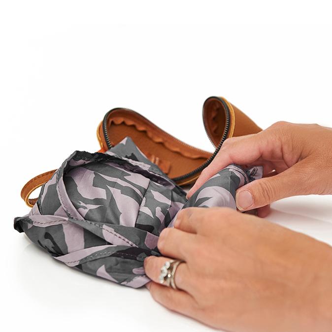 Womans hands folding up the pacsac into a small shape