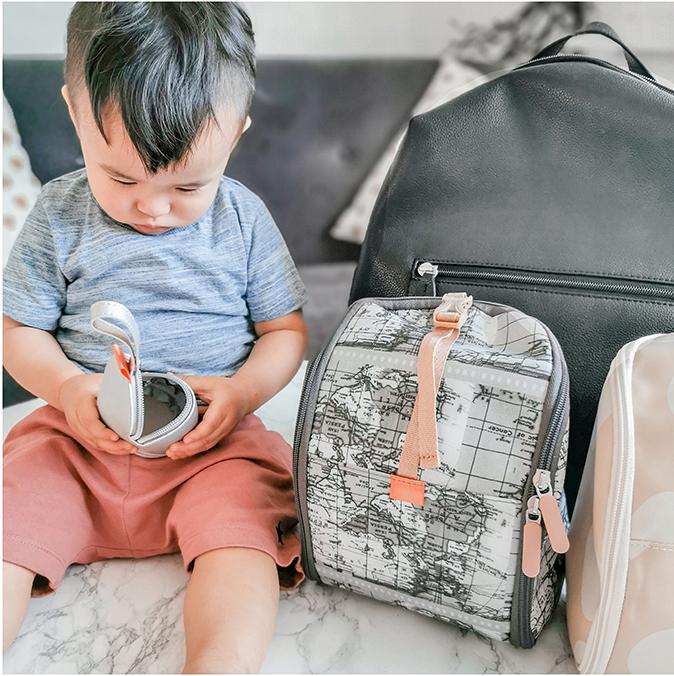Toddler sitting with a silver mini pod in his hands and pacapod pods beside him 