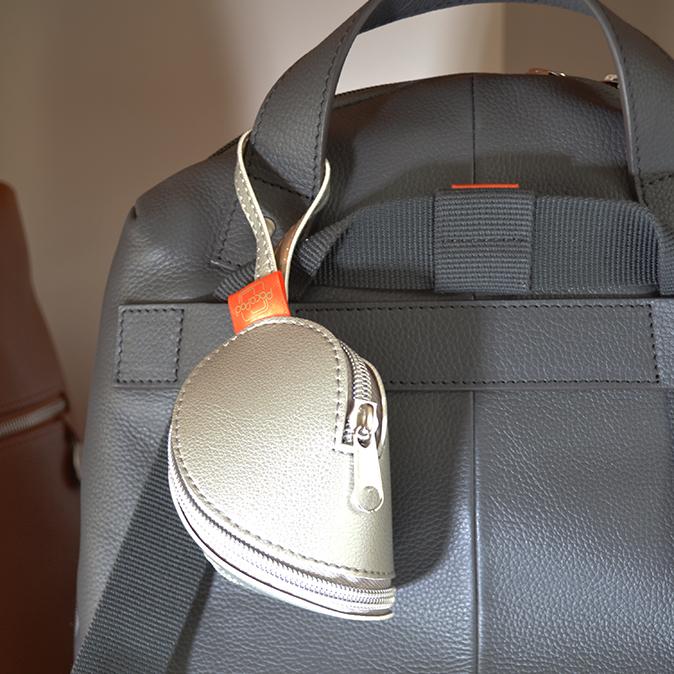 Silver minipod attached to the grab handle pf a grey pacapod changing bag