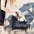 Hastings Knapsack changing bag with the feeder pod, changer pod, mat and pram clips beside it with a white background