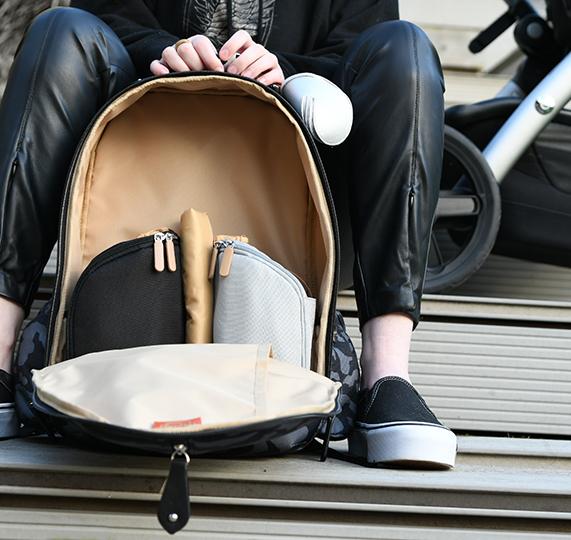 Woman sat on a step with an open picos backpack in front of her with the pods showing inside 